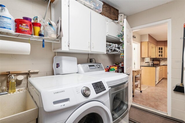 washroom with independent washer and dryer, light tile patterned floors, a sink, and cabinet space
