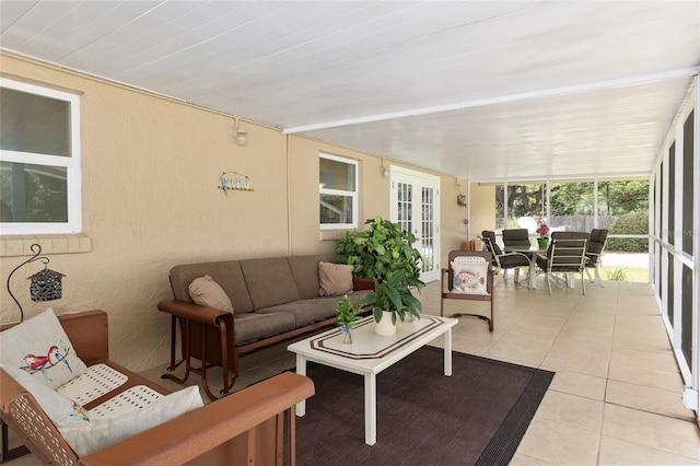 sunroom / solarium with a textured wall, tile patterned floors, and french doors