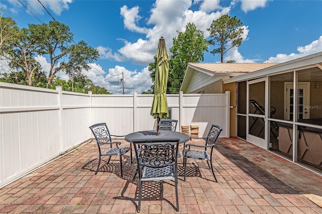 view of patio featuring a fenced backyard, outdoor dining space, and a sunroom