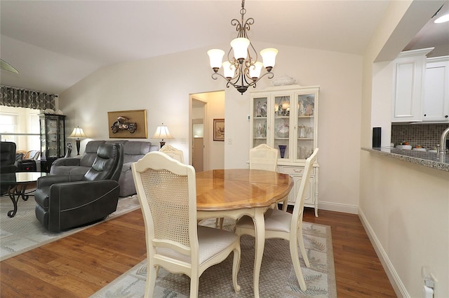 dining room with a chandelier, dark wood-style floors, baseboards, and lofted ceiling