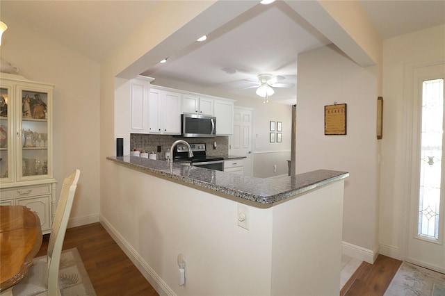 kitchen with a peninsula, wood finished floors, backsplash, and stainless steel appliances