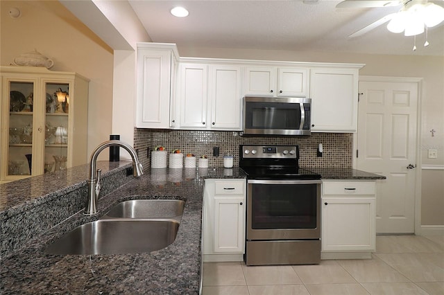 kitchen with light tile patterned floors, white cabinets, a sink, stainless steel appliances, and backsplash