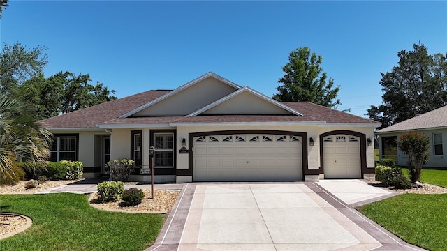 ranch-style home featuring stucco siding, roof with shingles, a front yard, an attached garage, and concrete driveway