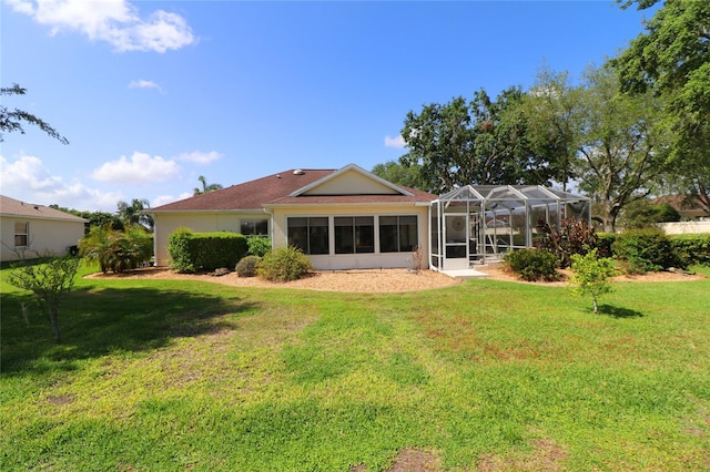 rear view of house featuring glass enclosure and a lawn