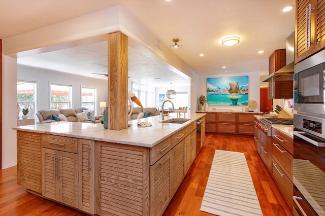 kitchen featuring a sink, stainless steel appliances, wood finished floors, open floor plan, and recessed lighting