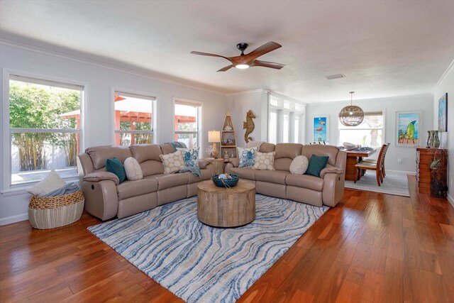 living area featuring healthy amount of natural light, ceiling fan, hardwood / wood-style floors, baseboards, and crown molding