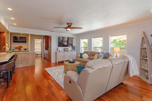 living area with crown molding, wood-type flooring, recessed lighting, and a ceiling fan
