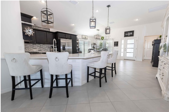 5325 Zisa Ct, The Villages, FL 32163 - kitchen with stainless steel fridge, light countertops, a breakfast bar area, decorative backsplash, and hanging light fixtures