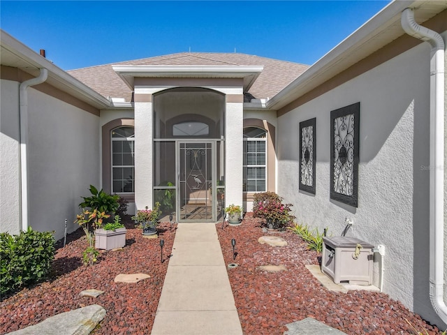 25523 Maurepas Ln, Leesburg, FL 34748 - view of exterior entry featuring roof with shingles and stucco siding
