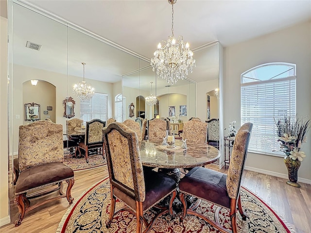 25523 Maurepas Ln, Leesburg, FL 34748 - dining area featuring arched walkways, light wood-type flooring, visible vents, a healthy amount of sunlight, and a notable chandelier
