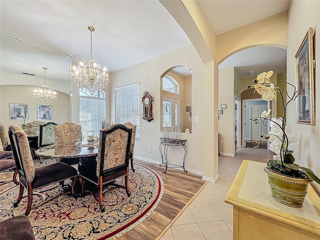 25523 Maurepas Ln, Leesburg, FL 34748 - dining space with an inviting chandelier, arched walkways, visible vents, light tile patterned flooring, and baseboards