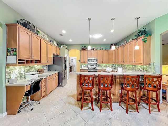 25523 Maurepas Ln, Leesburg, FL 34748 - kitchen featuring arched walkways, light countertops, appliances with stainless steel finishes, a peninsula, and backsplash