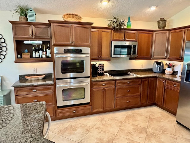 1985 Abordale Ln, The Villages, FL 32162 - kitchen featuring a textured ceiling, dark stone countertops, appliances with stainless steel finishes, light tile patterned flooring, and brown cabinets