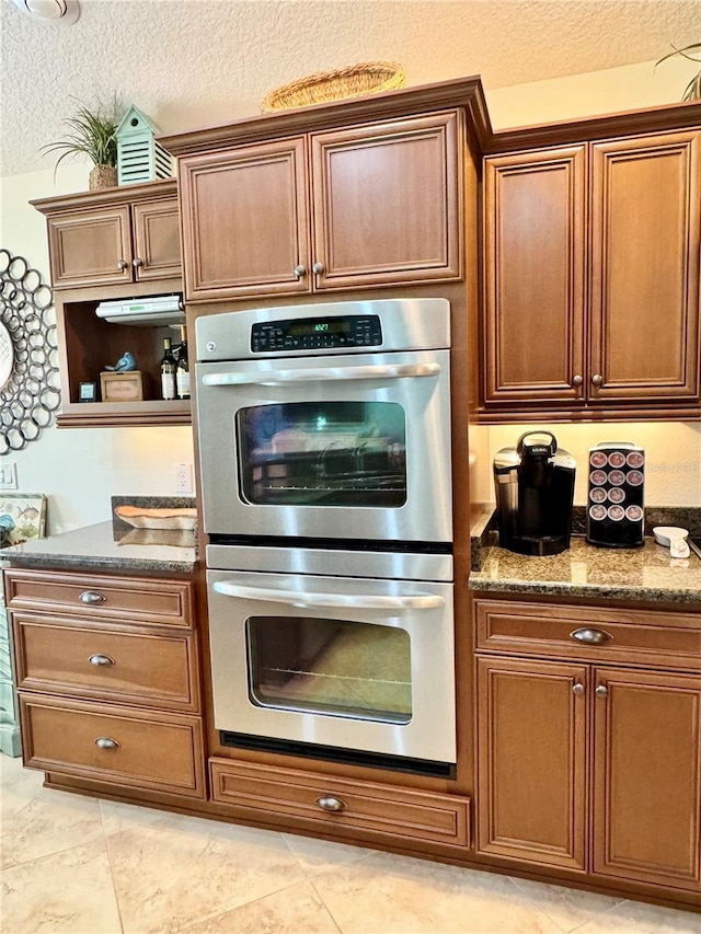1985 Abordale Ln, The Villages, FL 32162 - kitchen with dark stone countertops, a textured ceiling, open shelves, light tile patterned flooring, and stainless steel double oven