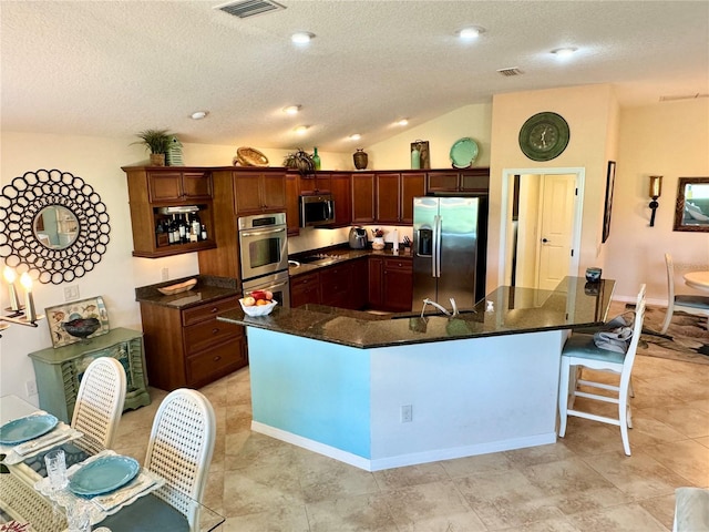 1985 Abordale Ln, The Villages, FL 32162 - kitchen with dark stone countertops, visible vents, appliances with stainless steel finishes, a textured ceiling, and a breakfast bar area