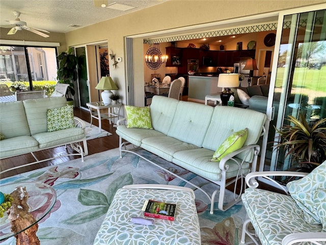 1985 Abordale Ln, The Villages, FL 32162 - living area featuring a textured ceiling, wood finished floors, and ceiling fan with notable chandelier