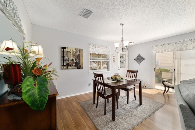 312 Emmalee Pl, The Villages, FL 32162 - dining area with visible vents, a chandelier, wood finished floors, and a textured ceiling