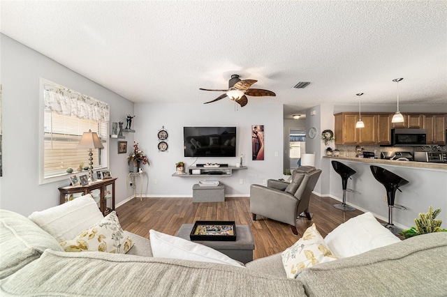 312 Emmalee Pl, The Villages, FL 32162 - living room with dark wood-type flooring, visible vents, a ceiling fan, and a textured ceiling