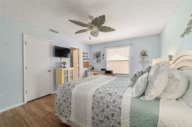 312 Emmalee Pl, The Villages, FL 32162 - bedroom with a textured ceiling, a ceiling fan, visible vents, wood finished floors, and baseboards