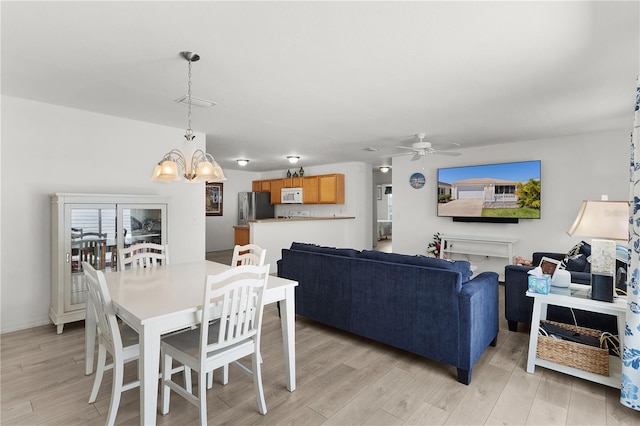 dining area with ceiling fan with notable chandelier and light wood-type flooring
