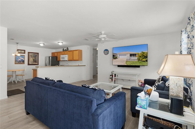 living room featuring ceiling fan, baseboards, visible vents, and light wood-style flooring