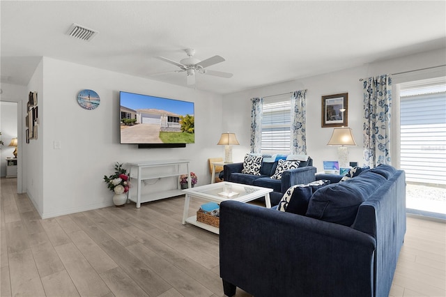 living room featuring baseboards, visible vents, light wood-style floors, and ceiling fan