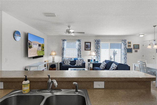 kitchen featuring a sink, open floor plan, visible vents, pendant lighting, and ceiling fan