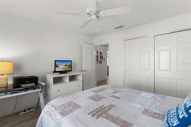bedroom with a closet, wood finished floors, visible vents, and ceiling fan