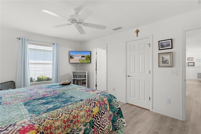bedroom with visible vents, light wood finished floors, baseboards, and ceiling fan