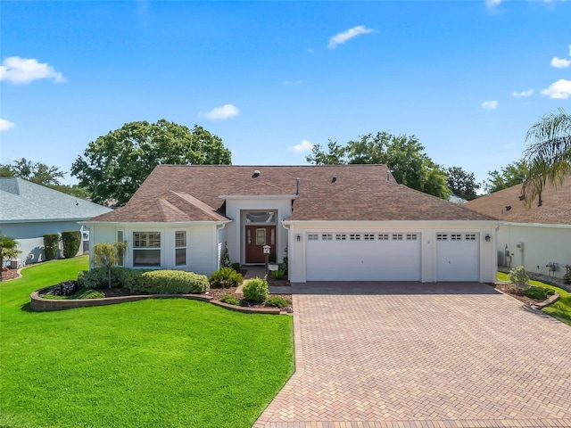 ranch-style house with roof with shingles, a front lawn, decorative driveway, and an attached garage