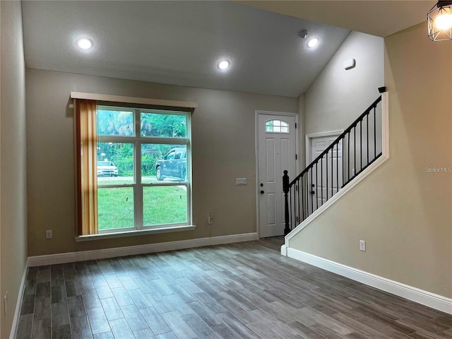 foyer entrance with baseboards, vaulted ceiling, wood finished floors, and stairs