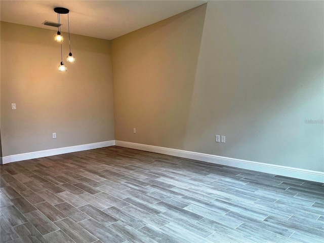 empty room featuring visible vents, baseboards, and wood finished floors