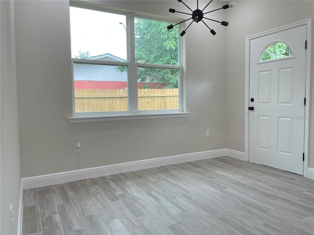 entrance foyer with a chandelier, baseboards, and wood finished floors