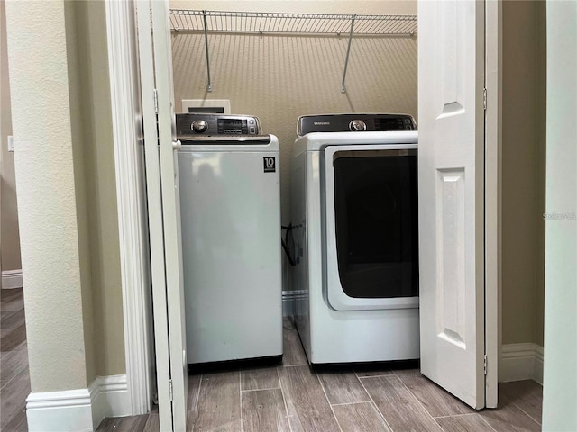 laundry area with laundry area, washing machine and clothes dryer, baseboards, and wood finish floors