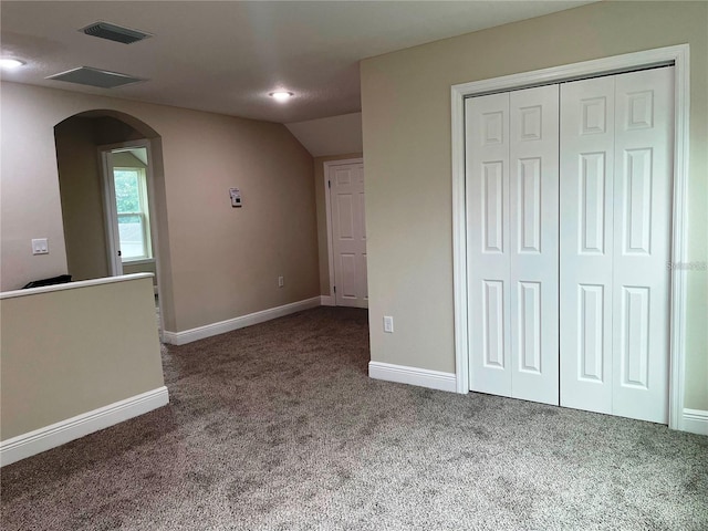 interior space featuring visible vents, baseboards, a closet, arched walkways, and carpet