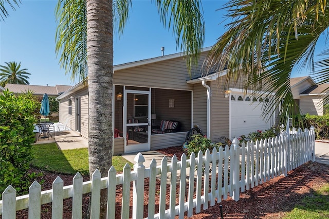 view of front of home with a garage, fence private yard, and a sunroom