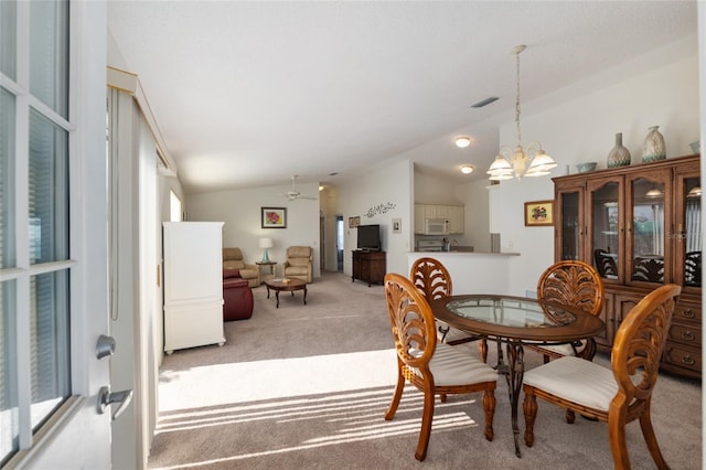 dining space featuring lofted ceiling, light colored carpet, visible vents, and ceiling fan with notable chandelier