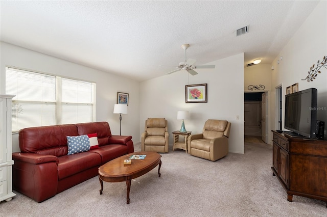 living area with lofted ceiling, a textured ceiling, visible vents, light carpet, and a ceiling fan