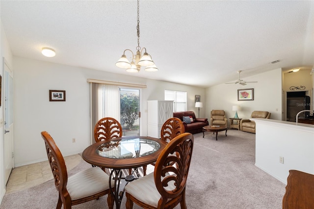 dining room featuring light colored carpet, visible vents, a textured ceiling, and ceiling fan with notable chandelier