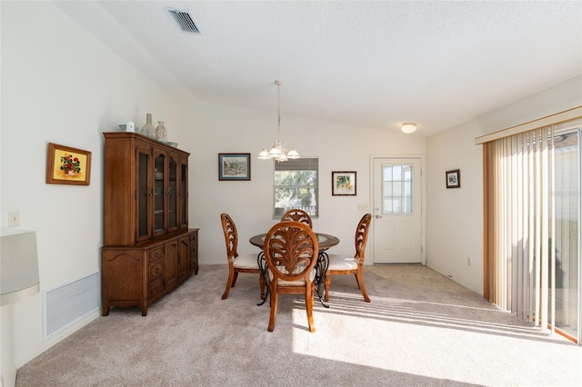 dining space with lofted ceiling, a chandelier, visible vents, and light carpet