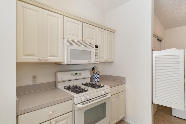 kitchen with light tile patterned floors, white appliances, light countertops, and cream cabinets