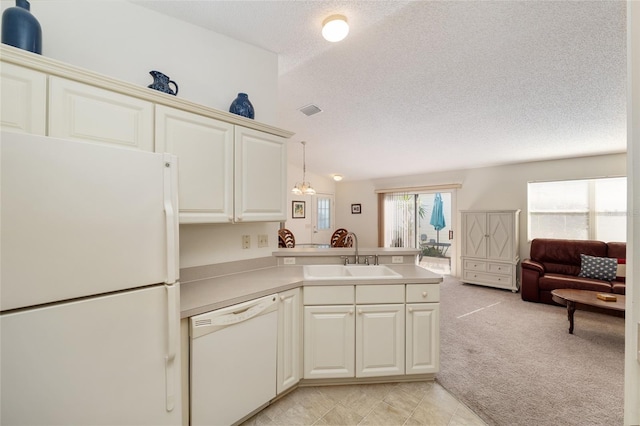 kitchen with a textured ceiling, a sink, open floor plan, white appliances, and a peninsula