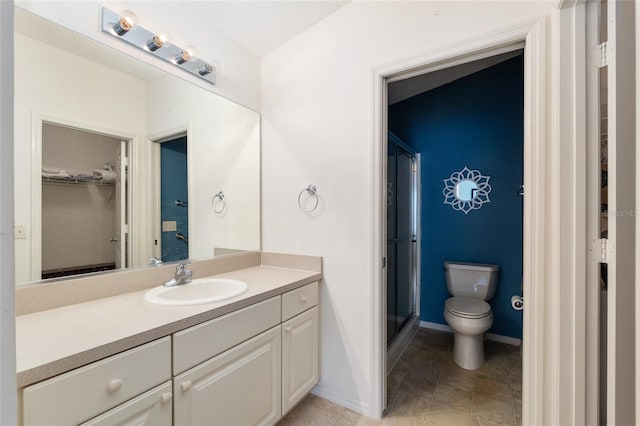 bathroom with vanity, tile patterned floors, toilet, a stall shower, and a spacious closet