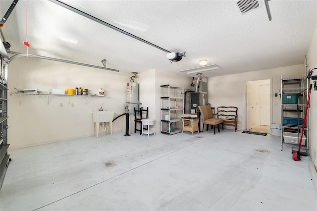 garage with a sink, heating unit, visible vents, and a garage door opener