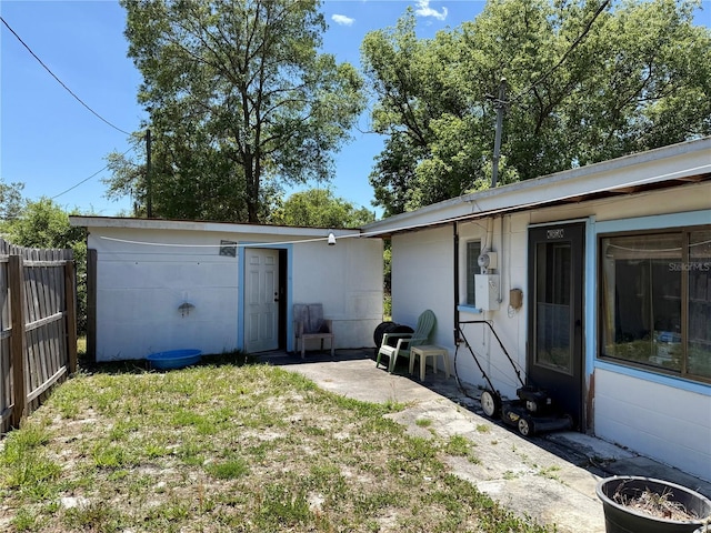 view of front of property featuring a patio area, fence, and an outbuilding