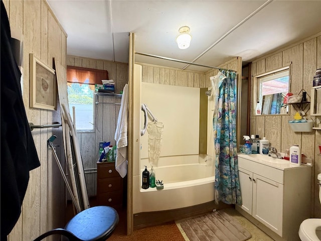 full bath with wooden walls, toilet, vanity, and shower / bath combo