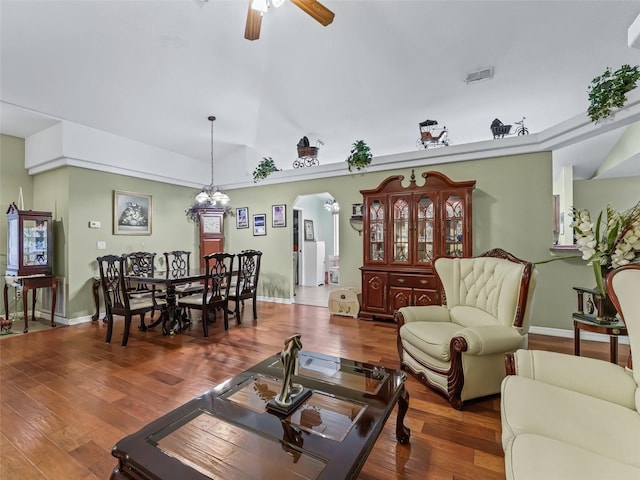 living room featuring wood finished floors, ceiling fan, arched walkways, baseboards, and visible vents