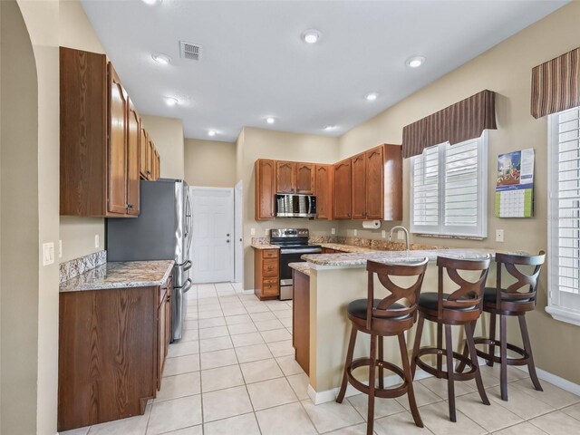 17787 SE 114th Ave, Summerfield, FL 34491 - kitchen featuring a kitchen breakfast bar, visible vents, light tile patterned floors, a peninsula, and appliances with stainless steel finishes