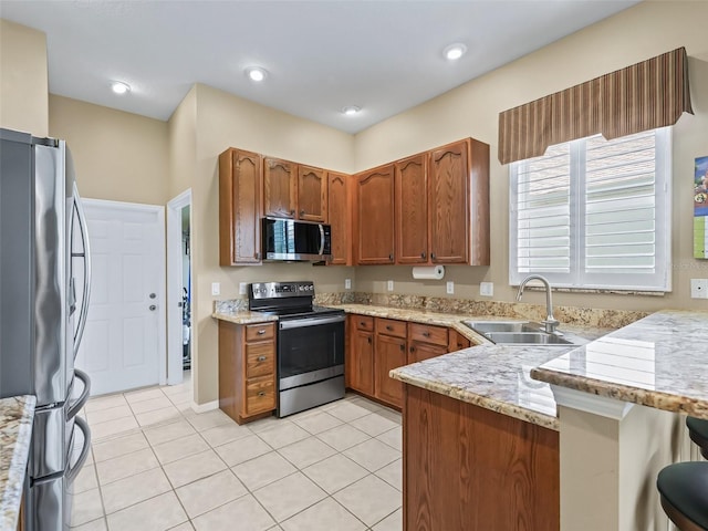 17787 SE 114th Ave, Summerfield, FL 34491 - kitchen with a sink, brown cabinetry, stainless steel appliances, a peninsula, and light stone countertops