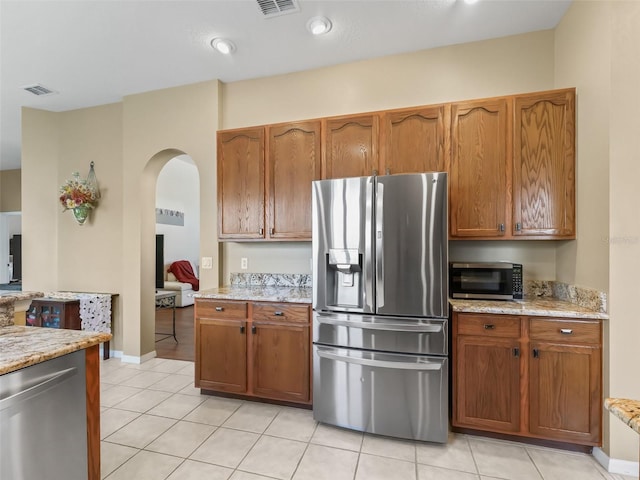 17787 SE 114th Ave, Summerfield, FL 34491 - kitchen featuring stainless steel appliances, arched walkways, light tile patterned flooring, visible vents, and light stone countertops